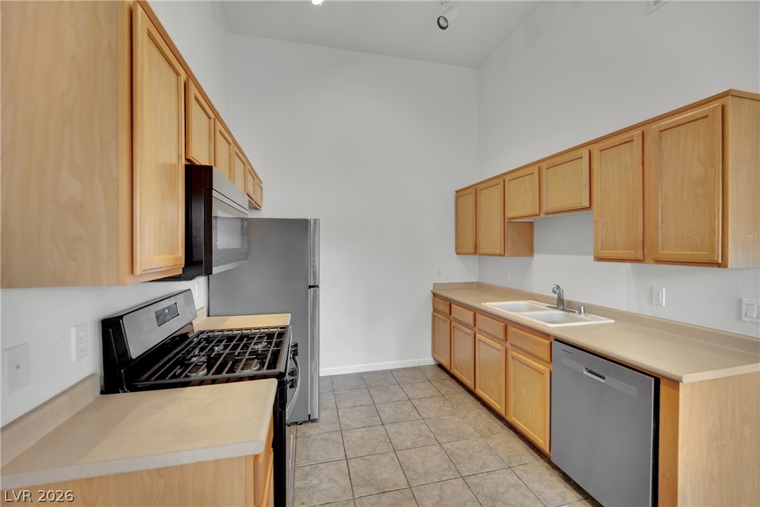 2305 West Horizon Ridge Parkway, Unit 2722 Henderson, NV 89052 - Photo 9 of 23 Kitchen featuring stainless steel appliances, light wood finish cabinetry, light countertops, light tile patterned floors, and a high ceiling