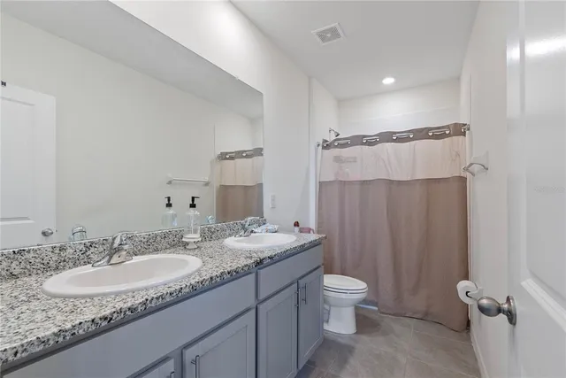 a bathroom with a granite countertop sink toilet a mirror a vanity and shower