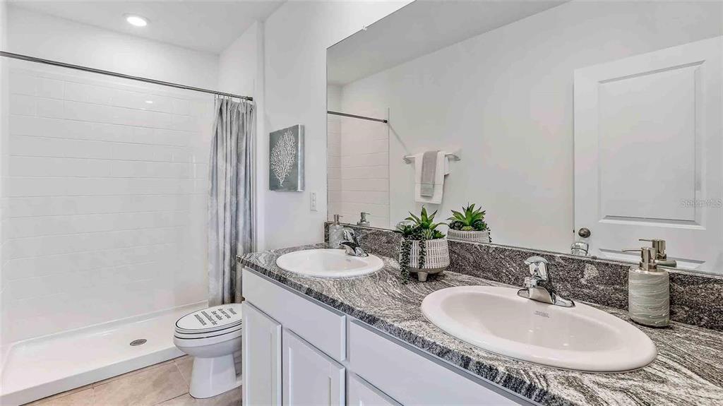 32395 Turtle Grace Loop Wesley Chapel, FL 33545 - Photo 25 of 39 a bathroom with a granite countertop sink a toilet a mirror and shower