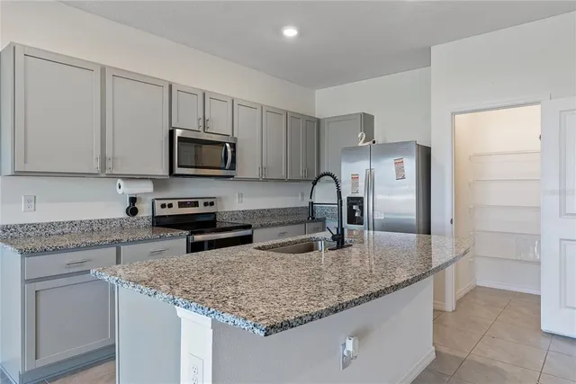 a kitchen with kitchen island granite countertop a sink stove and refrigerator