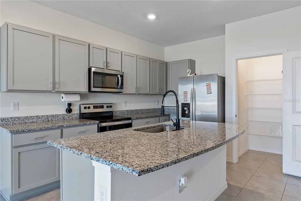 32395 Turtle Grace Loop Wesley Chapel, FL 33545 - Photo 8 of 39 a kitchen with kitchen island granite countertop a sink stove and refrigerator
