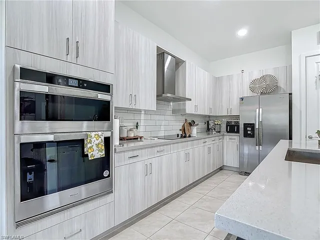 a kitchen with stainless steel appliances kitchen island granite countertop grey cabinets a stove a sink and a oven
