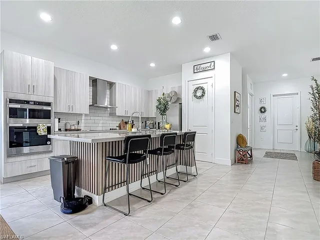 a kitchen with stainless steel appliances a stove a sink a refrigerator and chairs