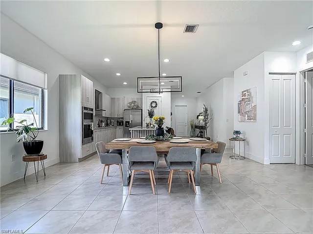 a view of a dining room and livingroom with furniture wooden floor a rug a painting and a chandelier