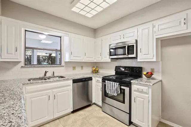 a kitchen with stainless steel appliances granite countertop white cabinets and black appliances