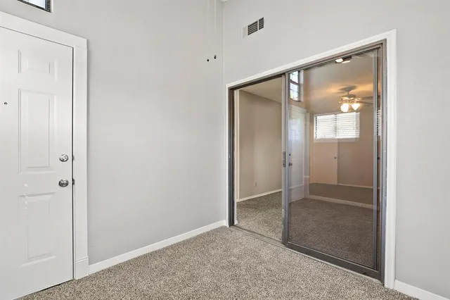 an empty room with windows and fan