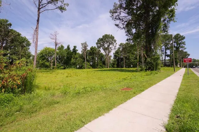 a view of a fountain in front of a house with a big yard and large trees