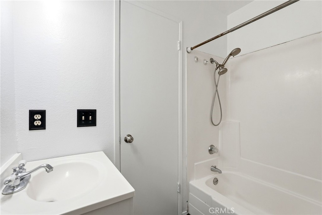 7890 East Spring Street, Unit 11E Long Beach, CA 90815 - Photo 37 of 40 a bathroom with a white bath tub sitting next to a white sink and a wooden vanity