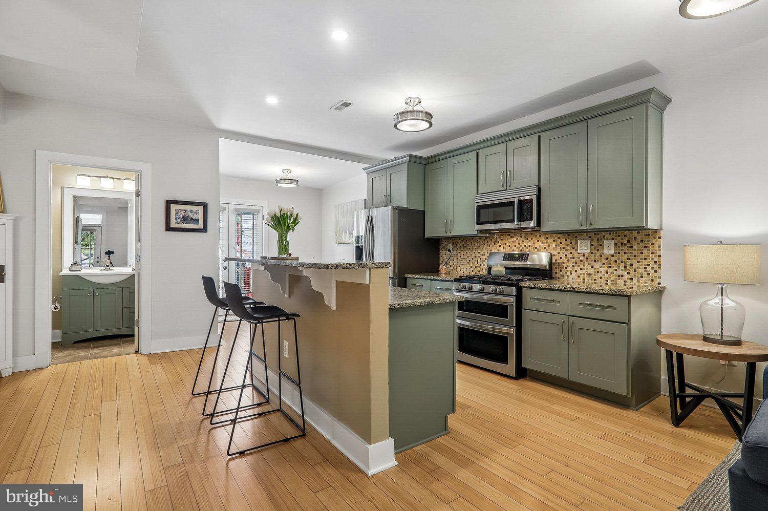 911 L Street Northeast Washington, DC 20002 - Photo 8 of 48 a kitchen with kitchen island granite countertop wooden floors and stainless steel appliances