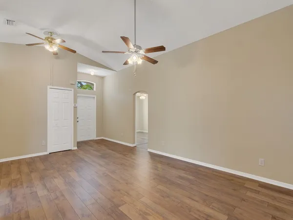 an empty room with wooden floor ceiling fan and window