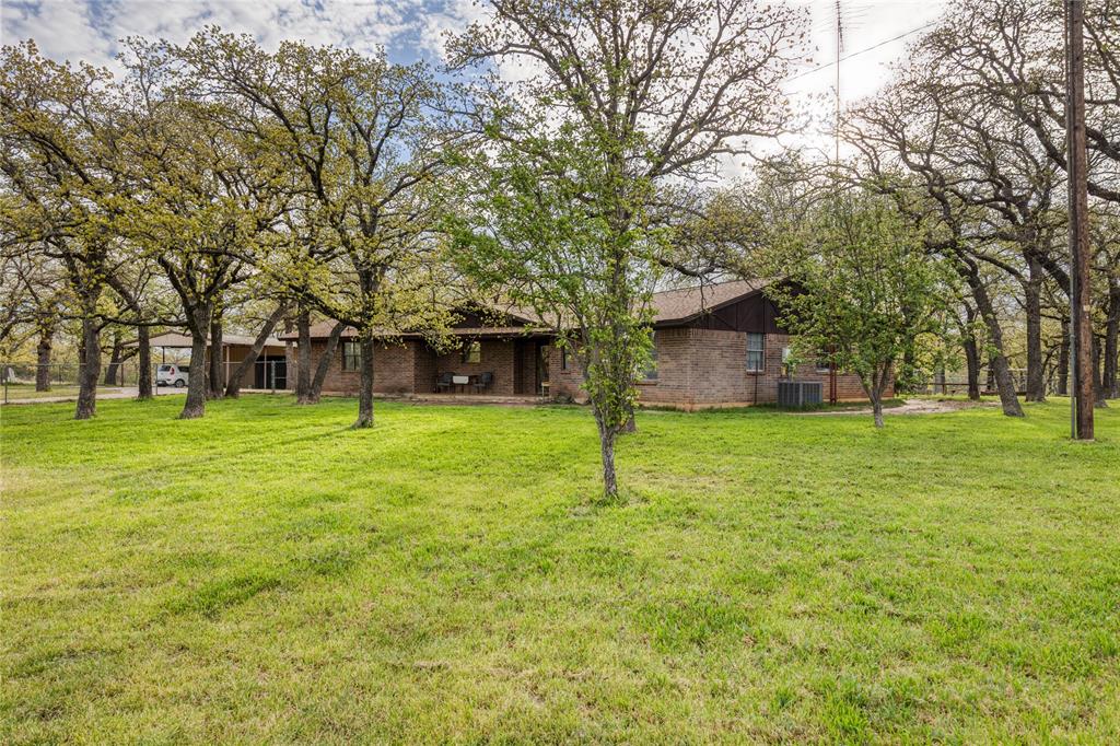 243 County Road 3851 Poolville, TX 76487 - Photo 2 of 34 a house with trees in the background