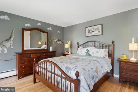 a bedroom with a bed a mirror on dresser and a window