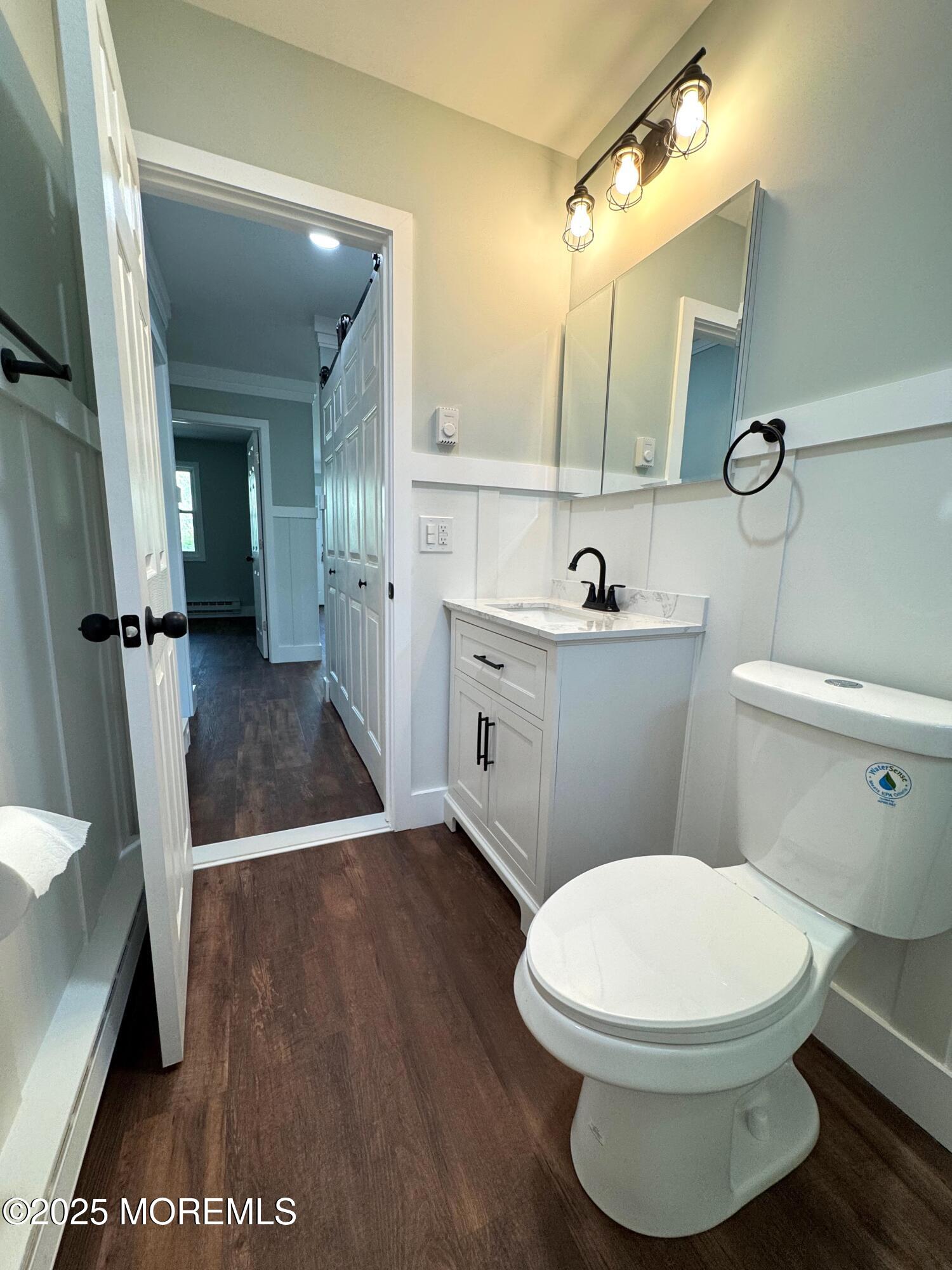 5 Nevada Drive Whiting, NJ 08759 - Photo 28 of 44 a bathroom with a toilet a sink a mirror and wooden floor