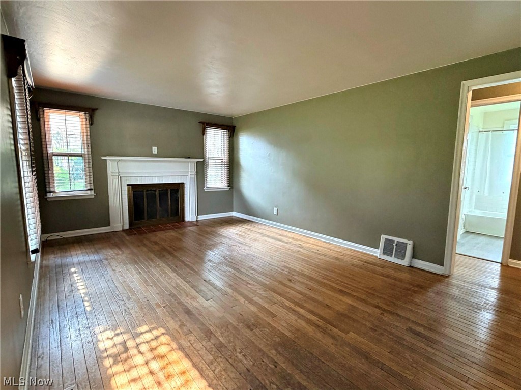 210 Callahan Road Canfield, OH 44406 - Photo 10 of 34 Hardwood flooring, central fireplace with white mantel, two windows with blinds, and painted walls