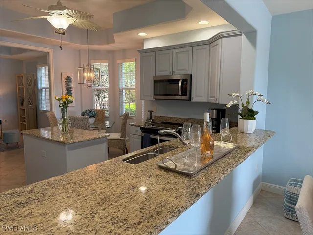 a kitchen with kitchen island granite countertop a sink counter top space appliances and cabinets