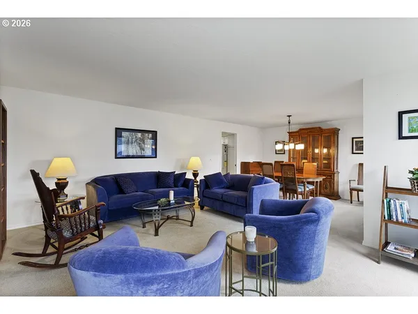 a living room with furniture a lamp paintings and a window