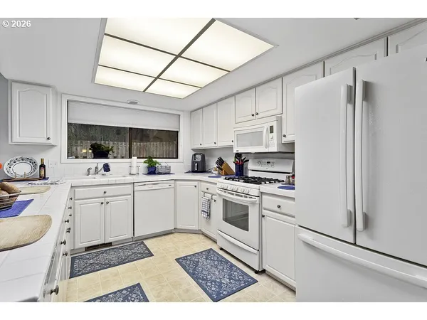 a kitchen with white cabinets a sink appliances and a counter top space