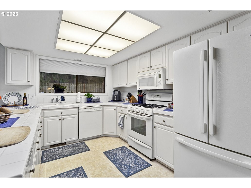 3788 Southeast 25th Street Gresham, OR 97080 - Photo 10 of 35 a kitchen with white cabinets a sink appliances and a counter top space
