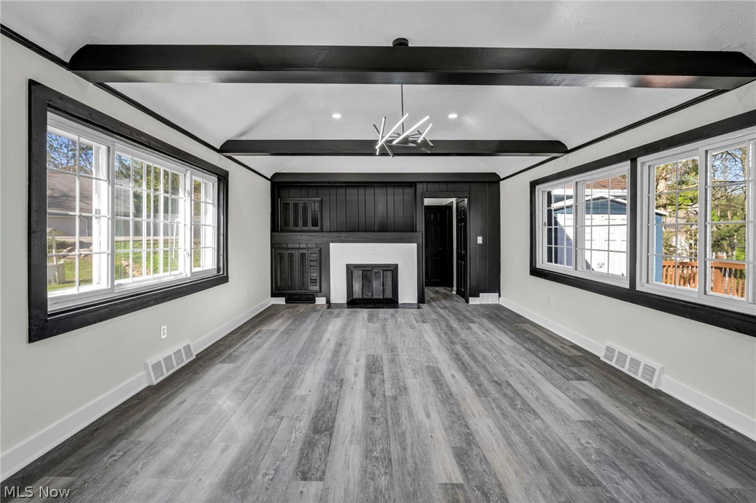 7339 River Road Olmsted Falls, OH 44138 - Photo 10 of 45 Spacious living area featuring exposed ceiling beams, wood-finish flooring, a contemporary chandelier, and a built-in fireplace with shelving