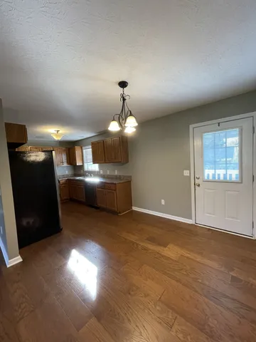 a view of an empty room with kitchen view and a window