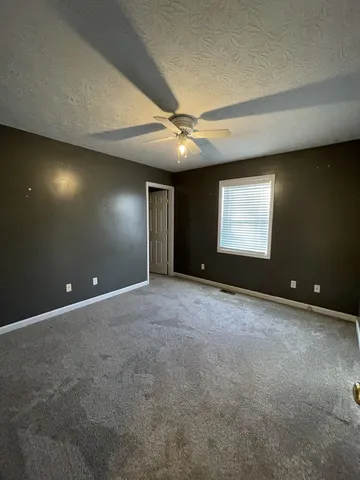 a view of an empty room with a ceiling fan and window