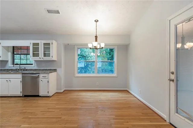 a kitchen with stainless steel appliances granite countertop white cabinets and wooden floor