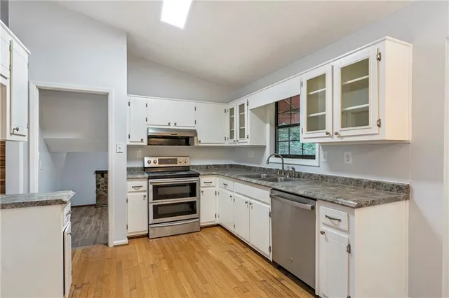 a kitchen with granite countertop a sink stainless steel appliances and cabinets