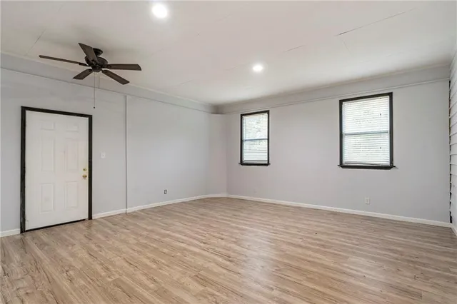 a view of empty room with wooden floor and fan