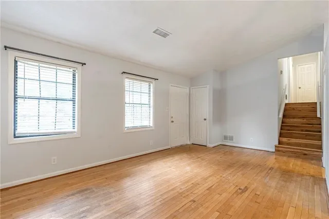 a view of an empty room with wooden floor and stairs