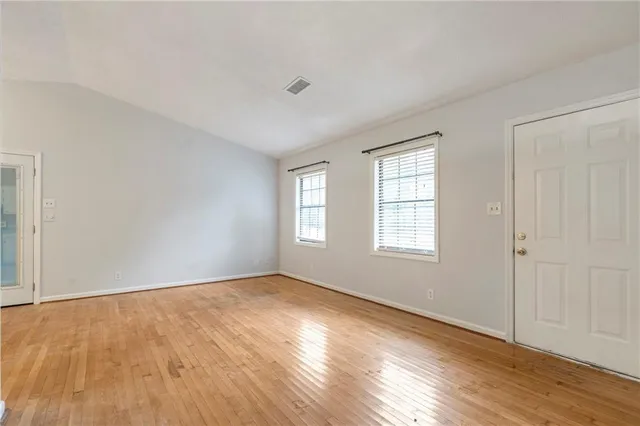 an empty room with wooden floor kitchen view and a kitchen