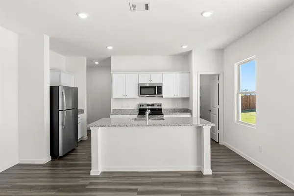 a view of a kitchen with a refrigerator a sink dishwasher and wooden floor