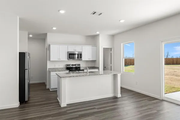 a kitchen with stainless steel appliances a stove top oven a refrigerator a sink and white cabinets with wooden floor