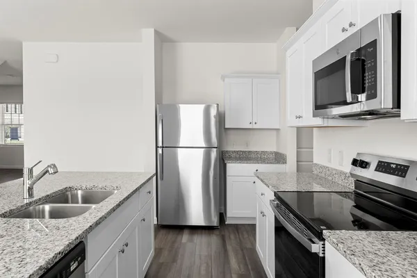 a kitchen with granite countertop a sink stove and refrigerator