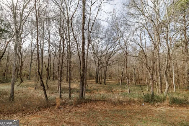 a front view of a house with large trees and fence