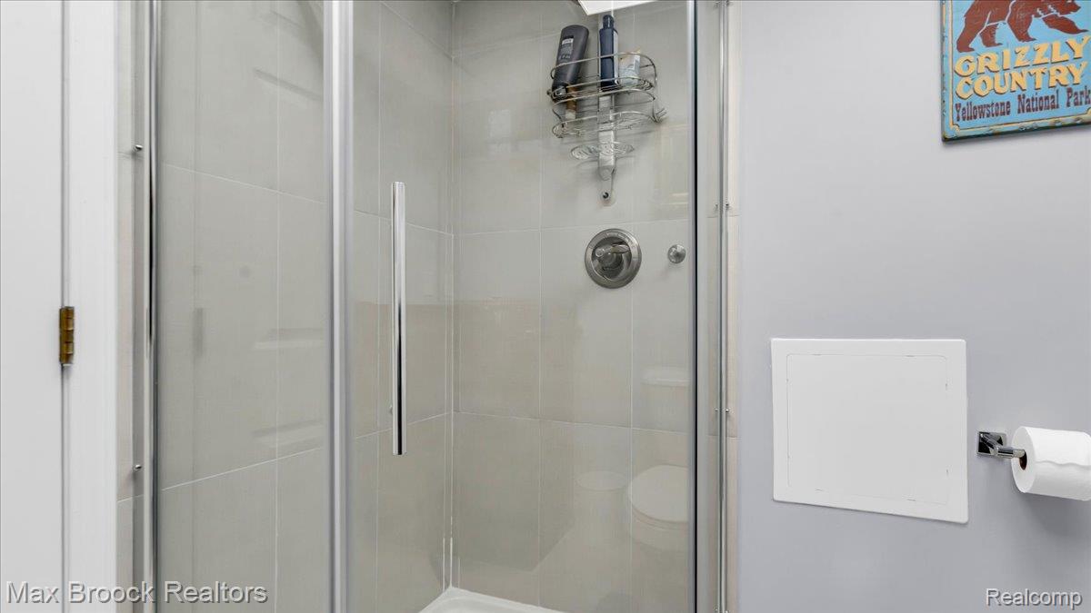 2253 Pembroke Road Birmingham, MI 48009 - Photo 39 of 56 Glass-enclosed shower with a chrome handle, light gray tile surround, and a circular shower control