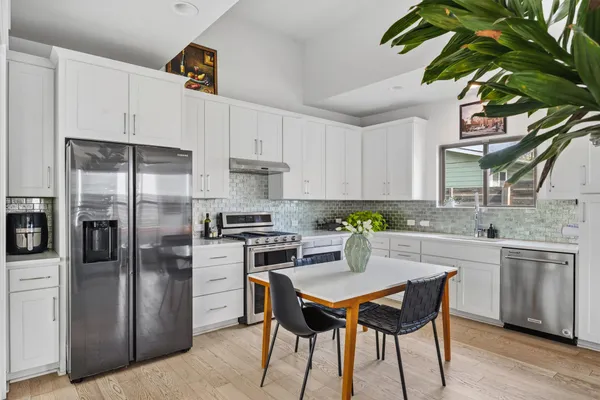 a kitchen with stainless steel appliances a dining table chairs stove refrigerator and cabinets