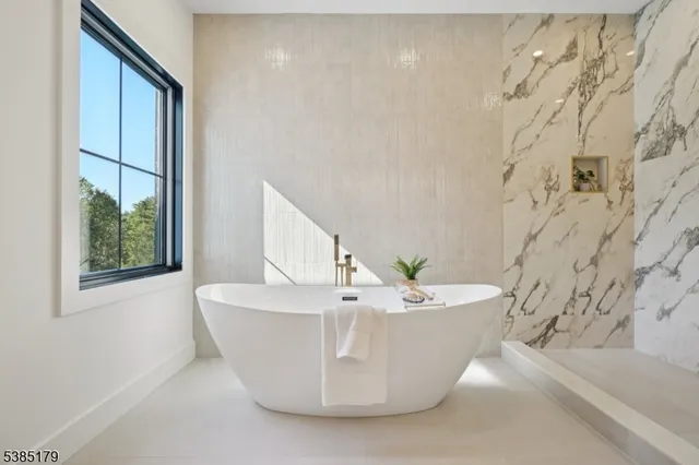 a white bath tub sitting in a bathroom next to a window