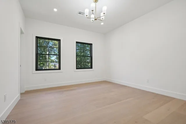 an empty room with windows and chandelier fan