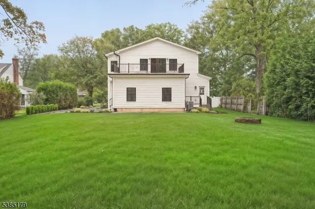 a white house with a big yard and large trees