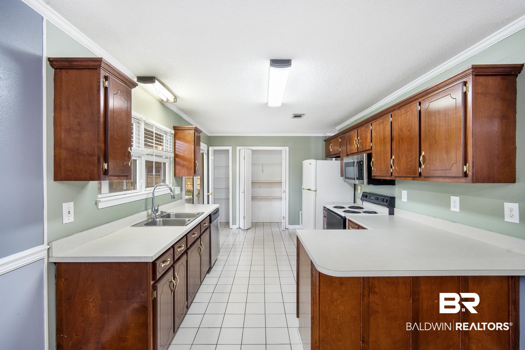 103 Ann Street Daphne, AL 36527 - Photo 6 of 23 Kitchen with crown molding, stainless steel appliances, light countertops, light tile patterned floors, and a peninsula