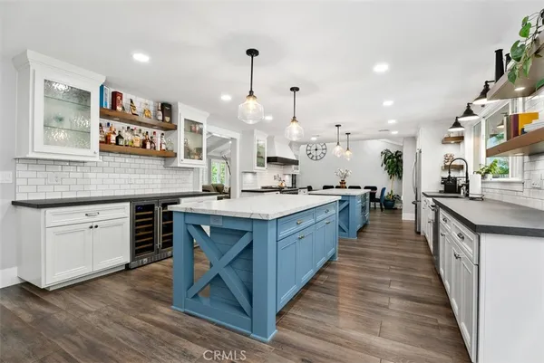 a kitchen with stainless steel appliances granite countertop a stove a sink dishwasher a refrigerator and a oven with wooden floor