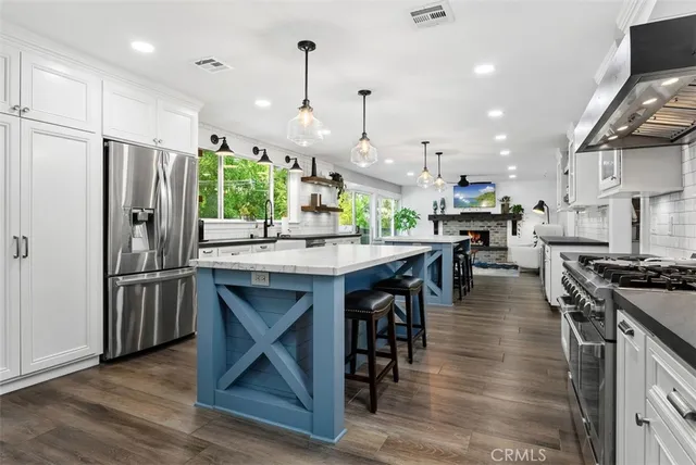 a large kitchen with stainless steel appliances granite countertop a stove and a wooden floors