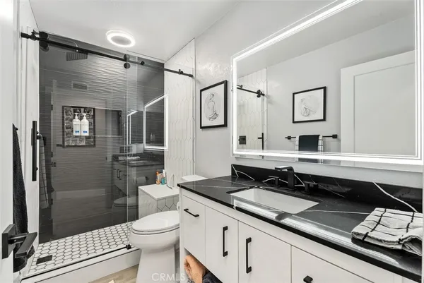 a bathroom with a sink a toilet a mirror and shower