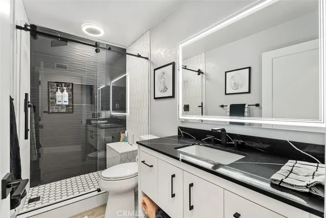 a bathroom with a sink a toilet a mirror and shower