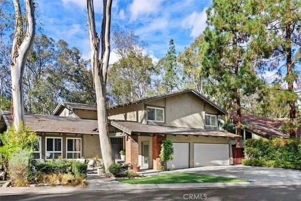 a view of a white house with large windows and a tree