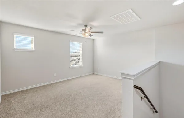 an empty room with windows and chandelier fan
