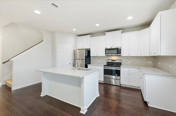 a kitchen with stainless steel appliances a stove a sink and white cabinets