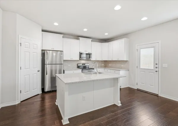 a kitchen with stainless steel appliances granite countertop a refrigerator and a stove top oven
