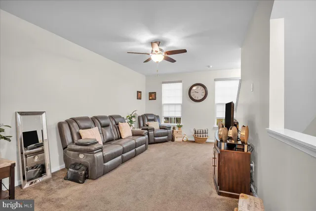 a living room with furniture a clock and a ceiling fan