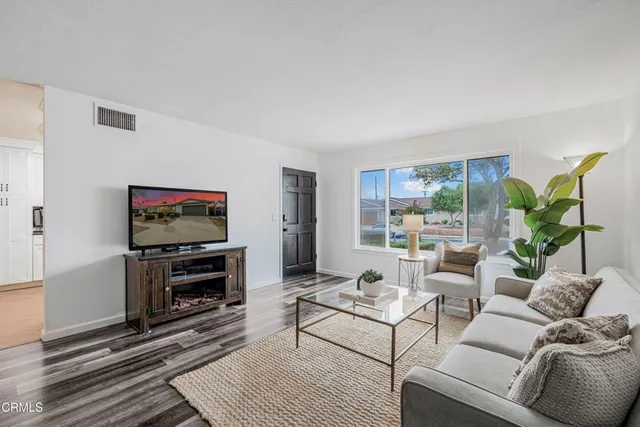 a living room with furniture a flat screen tv and a floor to ceiling window